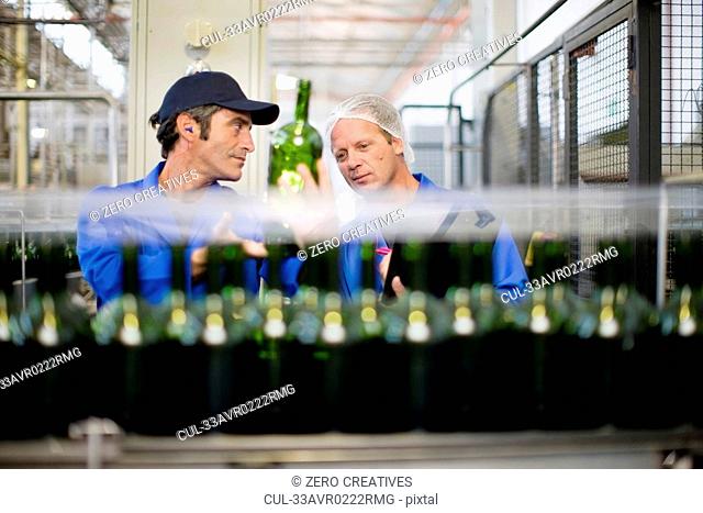 Workers checking bottles in factory