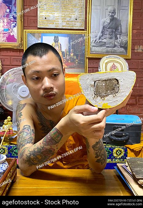23 June 2020, Thailand, -: Phra Anuchit Upanan, a monk in the Wat Samngam temple, shows the inside of a Kuman Thong, a baby figure which is supposed to contain...