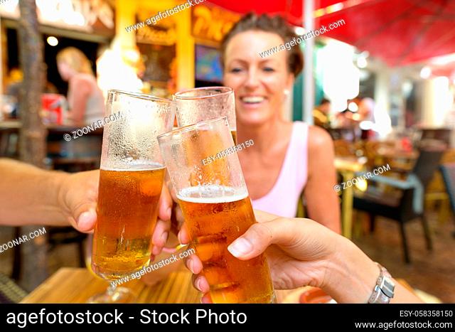 Portrait of Happy Friends Drinking and Toasting Beer Outdoors at Restaurant