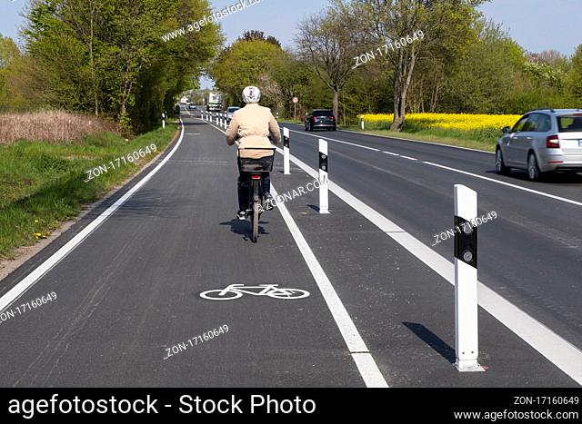 Radfahrerin auf Radweg mit Begrenzungspfosten, Kamen, Nordrhein-Westfalen, Deutschland, Europa