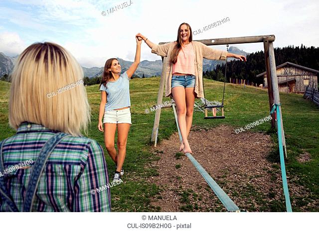 Three female adult friends balancing on slackline in Austrian Alps, Sattelbergalm, Tirol, Austria
