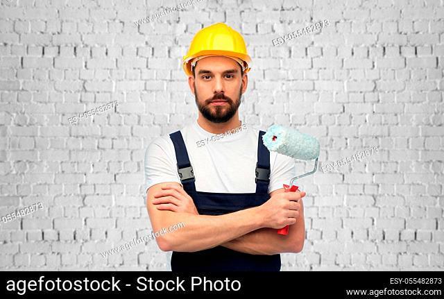 male builder with paint roller over brick wall