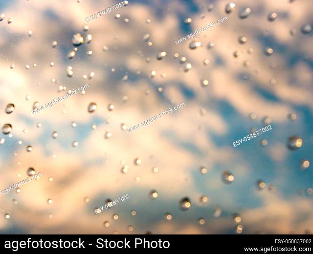 Blurred water drops of rain on blue glass with bokhe as background. Blurred rain drops on window