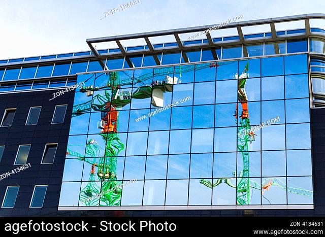 Baukräne spiegeln sich in der Glasfront eines Bürohauses am Kapelle-Ufer in Berlin, Deutschland