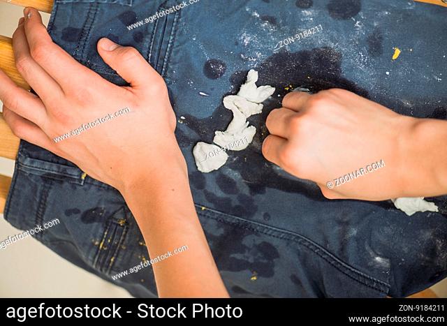 boy wipes the paint on his pants. Blue Jeans and sneakers stained with yellow paint. Top view