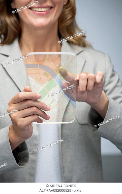 Woman using touch screen technology to view map on transparent digital tablet