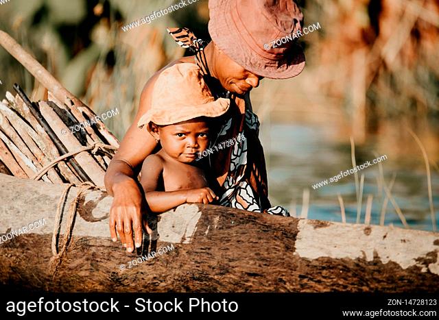 MADAGASCAR OCTOBER 18.2016 Malagasy woman with children from village transport freight by Traditional handmade dugout wooden boat