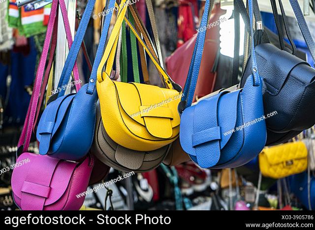 Many leather purse bags vibrant colors hanging on display in shopping street market