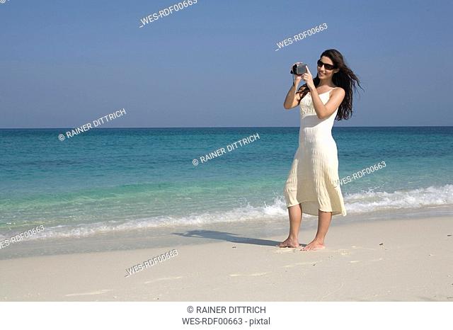 Asia, Thailand, Young woman filming on beach