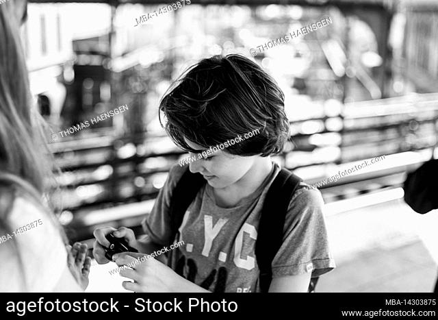Myrtle Av, New York City, NY, USA, 12 years old caucasian teenager boy - with brown hair and in summer outfit at the metro station