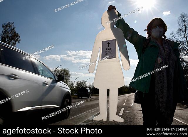 23 April 2022, Berlin: Annabelle Wolfsturm holds the figure of a child during a vigil on the street Landsberger Allee. The action was intended to draw attention...