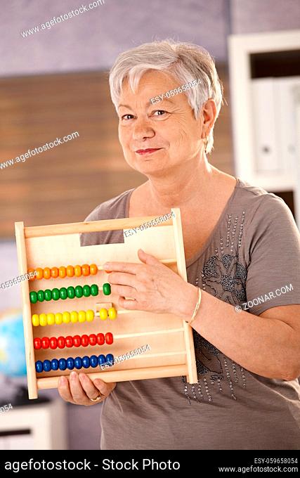 Senior teacher holding abacus, teaching math in elementary school