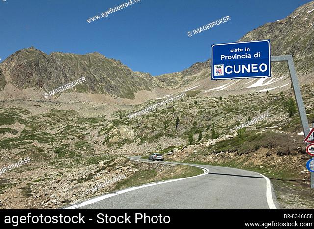 Porsche GT3 sports car crosses 2350 metre high Passo Lombarda pass on French-Italian border, above official information board traffic sign marking territory of...