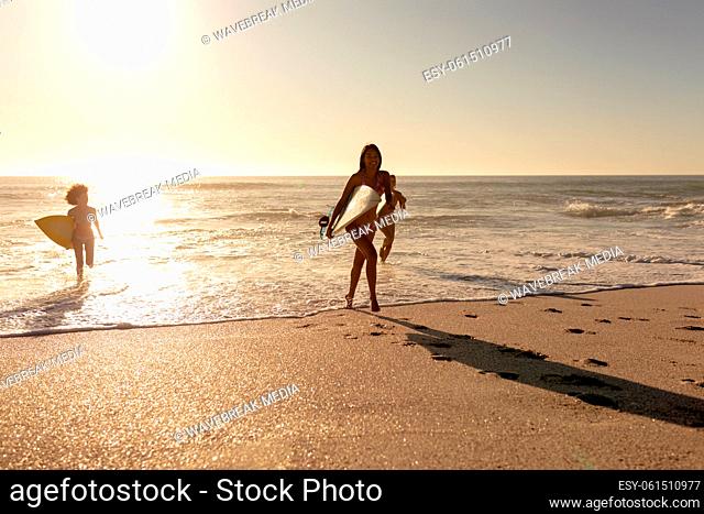 Young mixed race women holding surf boards on beach