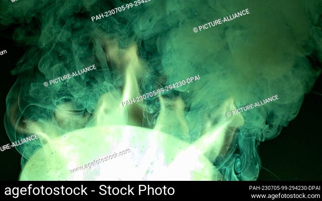 PRODUCTION - 05 July 2023, Saxony-Anhalt, Halle (Saale): A Bengal fire glows green in a chemistry laboratory at Martin Luther University in Halle/Saale