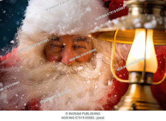 Santa Claus is holding a shining lantern while sneaking to his home outdoors at North Pole