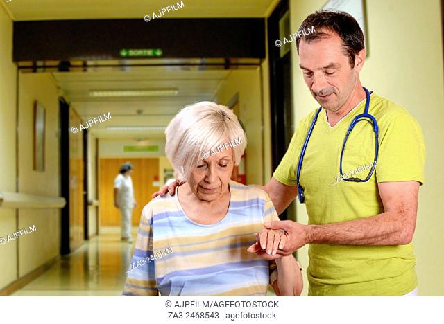 Doctor helping a elderly woman to walk in a hospital