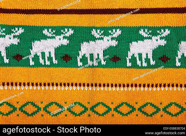 Christmas ornamental knitting with deers. knitted sweater background texture. Real knitted fabric textured background