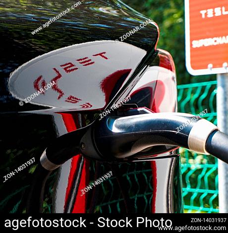 Maienfeld, GR / Switzerland - 30 June, 2019: detail of a Tesla car charging at the Tesla Super Charging Station in Maienfeld with reflections of supercharger...