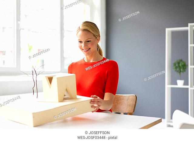Young woman in office looking at architectural model on desk