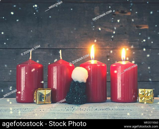 Four red Advent candles on a rustic wooden background, First candle is burning, Christmas concept background
