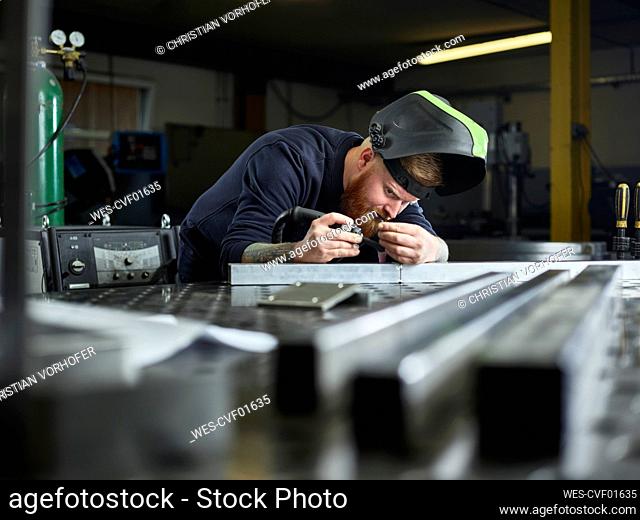 Metal technician examining material while working at factory
