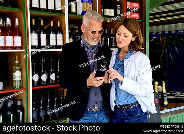 Mature couple choosing bottle of wine at a wine shop