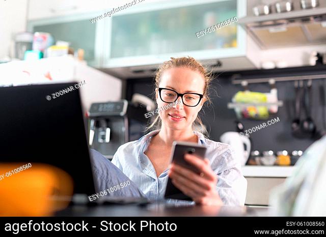 Stay at home and social distancing. Woman in her casual home clothing working remotly from her kitchen dining table in the morning