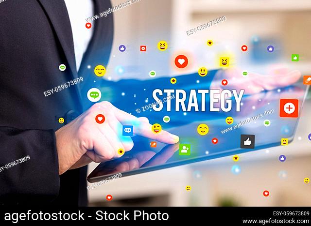 Close up of business person playing multimedia with social media icons and STRATEGY inscription