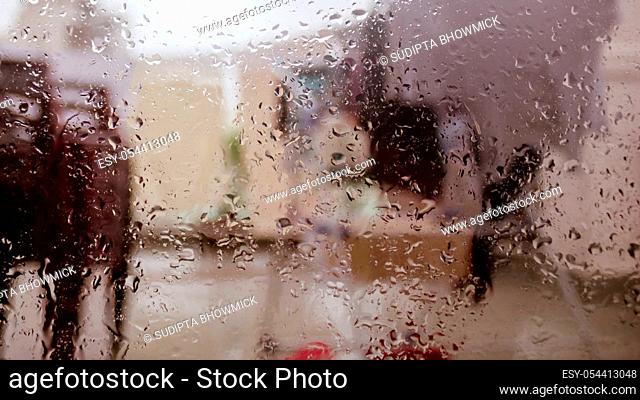 Rain Drops On Surface of wet Window Glass pane In Rainy Season. Abstract background. Natural Pattern of raindrops isolated from blurry city outdoor in a cloudy...
