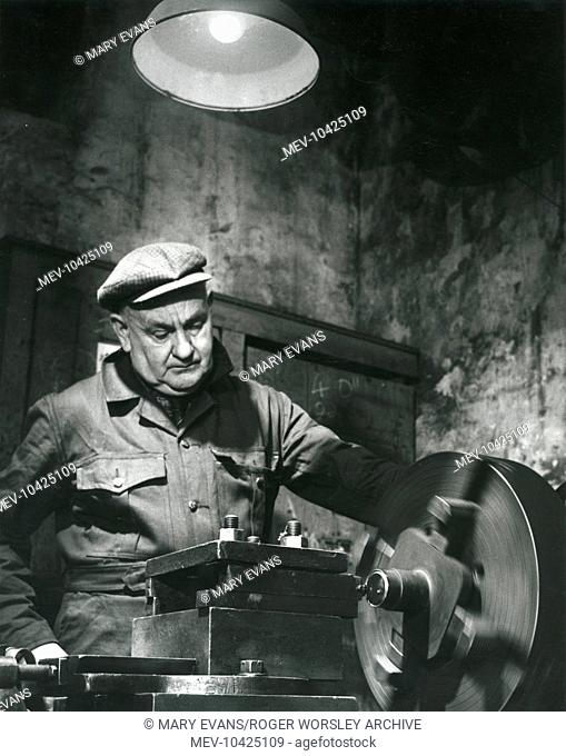 A man turning a new axle on a lathe in the machine shop at Dinorwig (or Dinorwic) Slate Quarry, near Llanberis, North Wales
