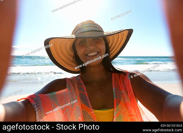 Smiling mixed race woman on beach holiday taking selfie