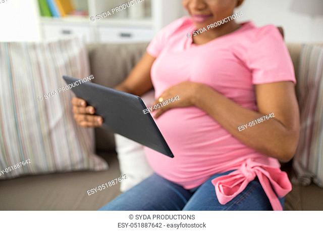 close up of pregnant woman with tablet pc at home