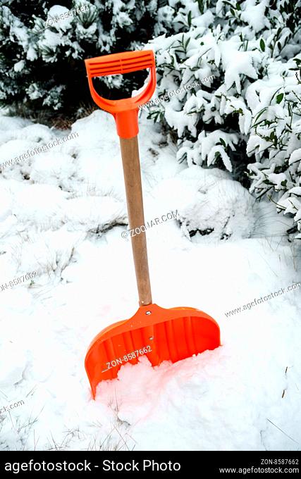 Snow removal. Orange Shovel in snow, ready for snow removal, outdoors