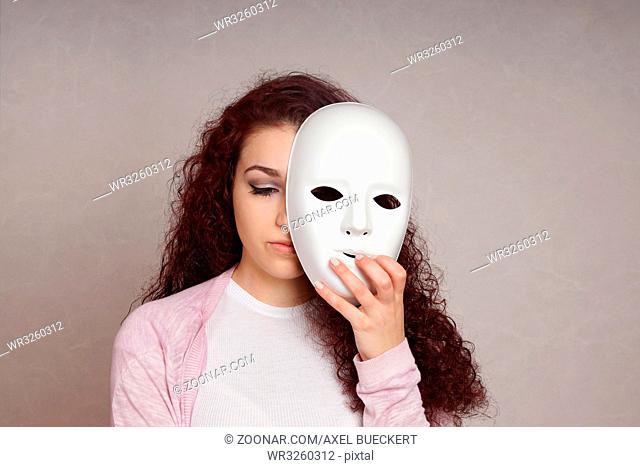 sad depressed young woman hiding her face behind mask