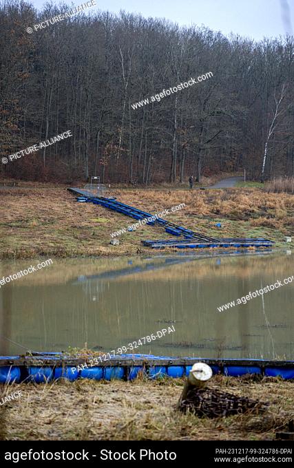 PRODUCTION - 15 December 2023, Bavaria, Stadtlauringen: A man goes for a walk on Lake Ellertshausen, a boat ramp next to him only leads to dry land