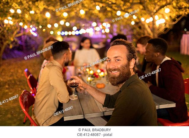 Portrait confident man drinking wine, enjoying dinner garden party