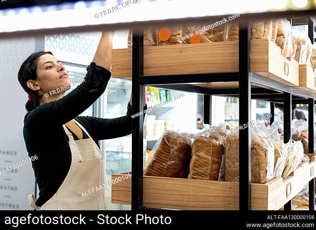 Mid-shot of female Latin-American bakery entrepreneur checking her merchandise