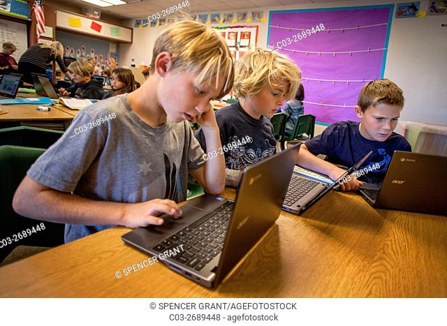 Three third grade boys enter information in their Google Chromebook laptop computers in a San Clemente, CA, elementary school classroom