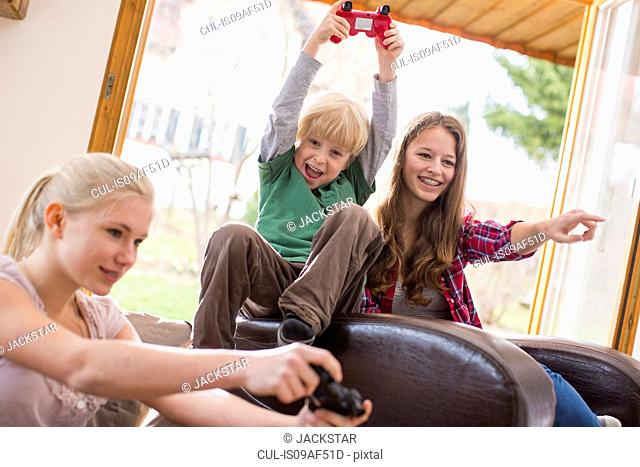 Teenage girls and boy playing games console