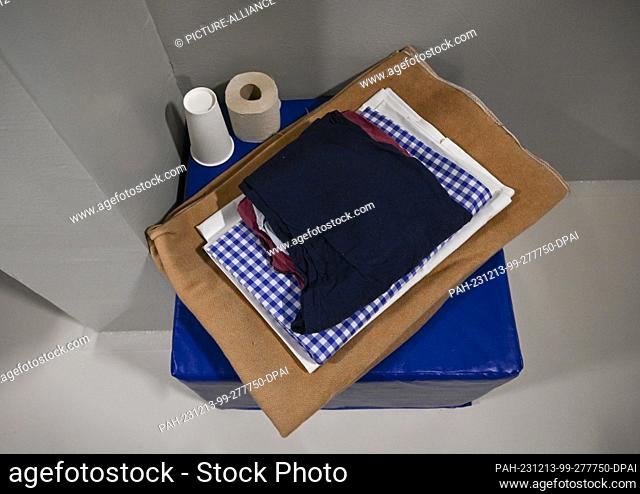 07 December 2023, Berlin: A blanket, clothes, bedding, toilet paper and a drinking cup are laid out for a prisoner in a specially secured room in Moabit Prison