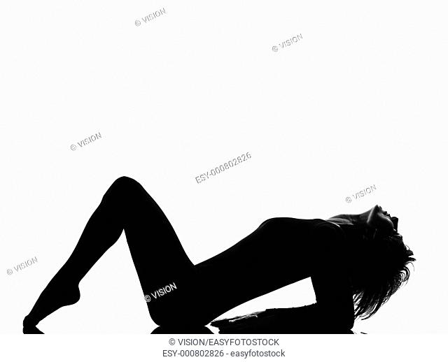 woman exercising lying on back fitness yoga stretching in shadow grayscale silhouette full length in studio isolated white background