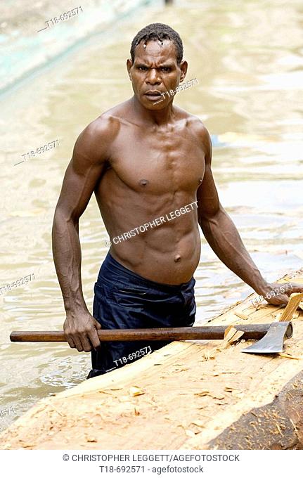 Woodsman making dug out in the river, Indonesia