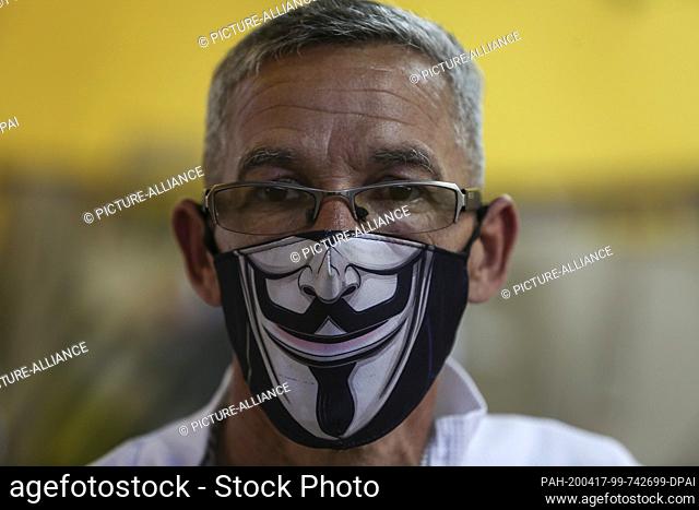 15 April 2020, Venezuela, Caracas: A man is wearing a face mask in the middle of the Corona pandemic with the image of the Anonymous mask on it