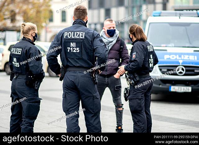 11 November 2020, Lower Saxony, Hanover: Police officers check the compliance with the mask obligation in front of the central station in the city centre