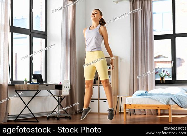 smiling teenage girl jumping on spot at home