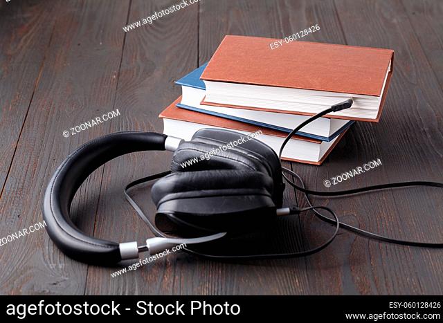 Audiobook concept with headphone and paper book on table