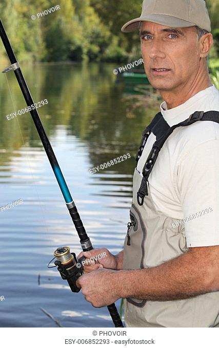 50 years old man fishing on the edge of a river