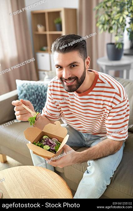 smiling man eating takeaway food at home