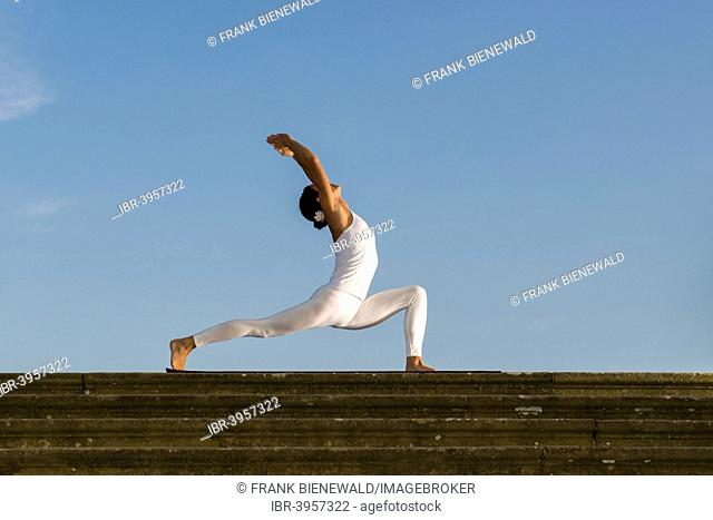 Young woman practising Hatha yoga, outdoors, showing the pose Anjaneyasana, Chandrasana, Half moon pose